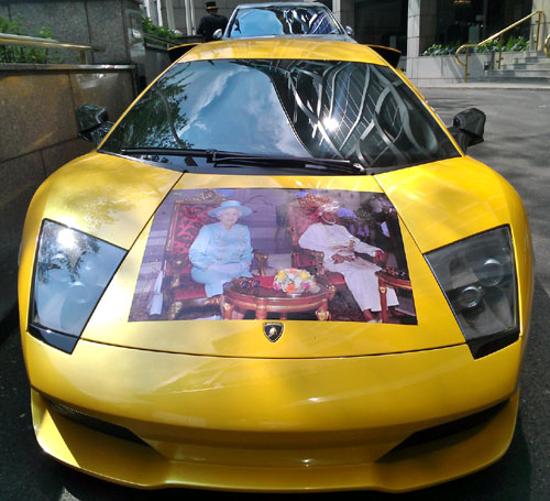 Picture of Queen Elizabeth II and the Sultan of Oman on the hood of a Yellow Lamborghini Gallardo